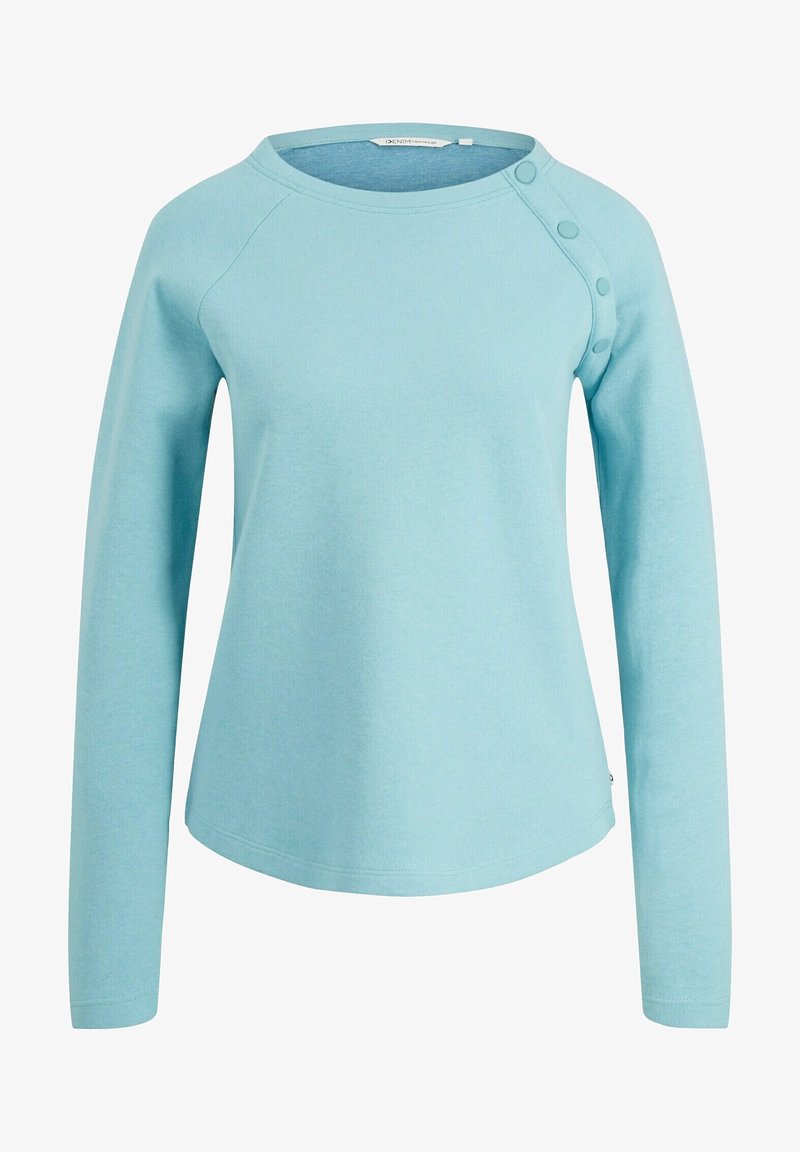 Ljusblå långärmad topp med rundad halsringning, raglanärmar och knappdetaljer på ena axeln. Tillverkad av ett mjukt, texturerat tyg.