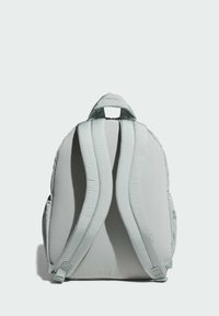 Zaino grigio chiaro con spallacci imbottiti e finitura testurizzata. Caratterizzato da una maniglia superiore e tasche laterali, presenta un design minimalista.