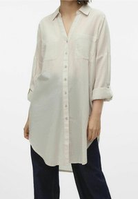 Camicia a righe chiara con colletto, due tasche sul petto, maniche arrotolate e orlo curvo, realizzata in un tessuto morbido e leggero.