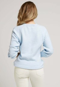 Pull léger bleu en matière douce, avec un col rond et des manches longues à coupe décontractée. Design simple sans motifs.