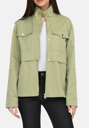 Chaqueta verde claro con cremallera, hecha de algodón, que presenta un cuello alto, dos bolsillos en el pecho con solapas y mangas largas.