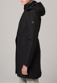 Parka noire imperméable avec capuche, au toucher lisse, dotée de poches avant et d'une silhouette élégante. Comprend un logo subtil sur la manche.