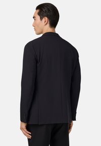 Černý sartorialní blazer, hladká tkanina, strukturovaný střih, klopové límce, jediný rozventil, knoflíkové manžety, elegantní design, moderní silueta.