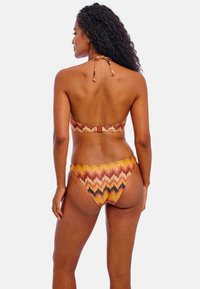 Bikini-set met een meerkleurig zigzagpatroon in oranje, bruin en geel. Gemaakt van een gladde stof met strikjes bij de nek en de rug.