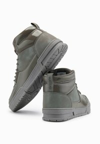 Zapatillas altas en verde apagado, con una mezcla de texturas mate y brillantes, suela de goma, punta redondeada y cierre de cordones.