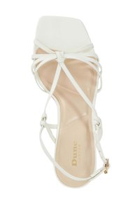 White high-heeled sandal with crisscross straps, square toe, and a nude footbed. Features a gold logo and an adjustable ankle strap.