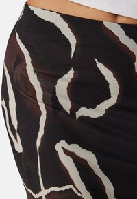 Zwarte rok met abstract wit en bruin patroon, met een soepele stoftextuur en een getailleerde pasvorm, die de complexe ontwerpdetails benadrukt.
