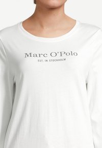 Witte longsleeve t-shirt van zachte stof, met een ronde halslijn en een grijs gedrukt logo met de tekst "Marc O'Polo EST. IN STOCKHOLM."