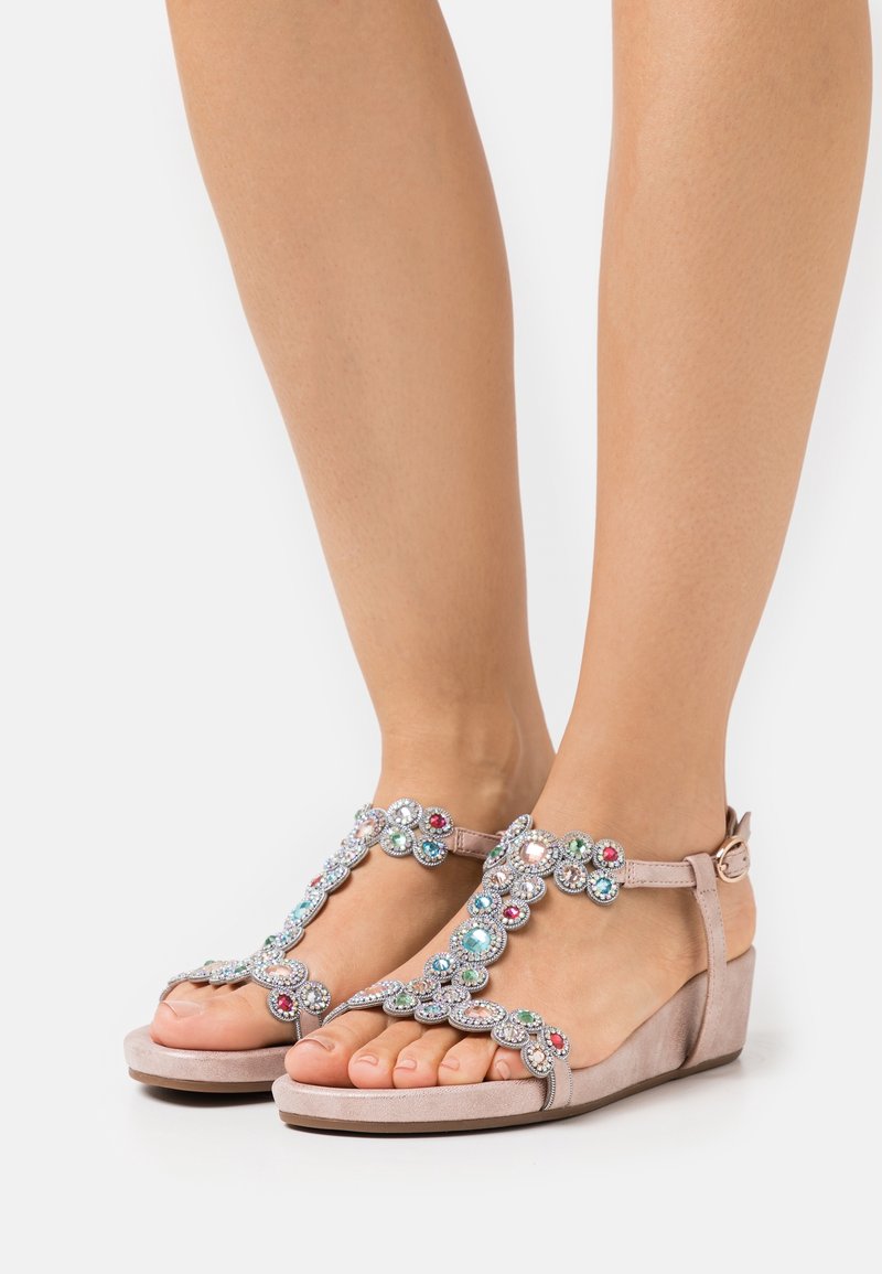 Sandales compensées beiges avec embellissements en bijoux, sangle de cheville ajustable, bout ouvert et texture lisse.