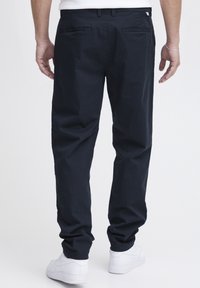 Granatowe bawełniane spodnie o luźnym kroju, z tylnymi kieszeniami i paskiem w talii. Połączone z białymi sneakersami.