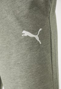 Pantalones de chándal en gris jaspeado de algodón con una textura suave, que presentan un logo blanco de Puma en el muslo izquierdo y un corte ajustado.