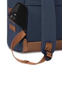 Borsa blu navy con dettagli marroni, dotata di una tasca con zip che contiene uno smartphone nero. Visibile il tessuto resistente e il dettaglio della tracolla regolabile.