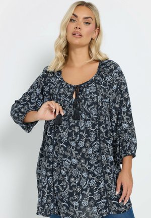 Blusa floreale blu navy con maniche lunghe, caratterizzata da un colletto a girocollo, dettaglio a chiave e frange. Motivo floreale in azzurro chiaro e bianco.