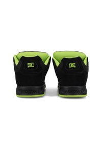 Zapatillas de ante negras con detalles de malla en verde lima; con cuello acolchado, suela de goma y logotipo embossado en el talón. El contrafuerte y la lengüeta coinciden en color.