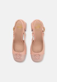 Ρόζ πατενταδέρμα τακούνια με στρογγυλή μύτη, που διαθέτουν κεντρικό λογότυπο "M", λουριά στον αστράγαλο και χαμηλό τετράγωνο τακούνι. Λείος υφή.