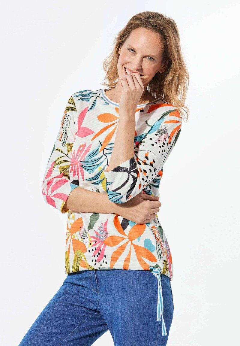 Bunt gemusterte Bluse mit drei Viertel Ärmeln, rundem Ausschnitt und verstellbaren Seitenschnüren. Aus leichtem Stoff mit glatter Textur gefertigt.