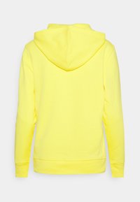 Felpa giallo con tasca a marsupio frontale, maniche lunghe e cappuccio. Realizzata in tessuto morbido con polsini e fondo a costine.
