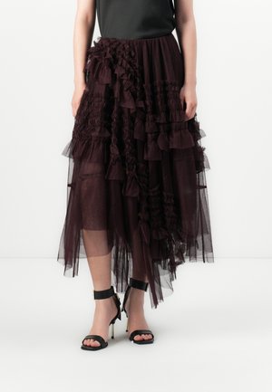 Jupe en tulle bordeaux avec des volants superposés et un ourlet asymétrique, associée à des escarpins à bride de cheville noirs, créant un look texturé.