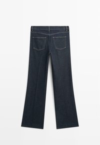 Granatowe dzwony z denimu o gładkiej fakturze, z pięcioma szlufkami na pasek i dwoma tylnymi kieszeniami ze zdwojonym przeszyciem.