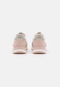 Sneakers with a soft pink suede heel and beige leather upper, featuring gray accents and a looped tab at the back for easy wearing.