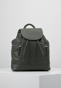 Sac à dos en cuir vert foncé avec un rabat repliable, fermeture à cordon, et poches zippées à l'avant. Texture lisse et accents en métal argenté.