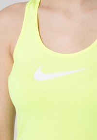 Débardeur de sport jaune néon avec un col arrondi et des bretelles fines, arborant un logo Nike swoosh blanc sur le devant. Texture lisse.