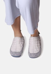 Quilted grey and light beige slippers with a soft textured upper and a grey felt sole, featuring a pull tab for easy wear.
