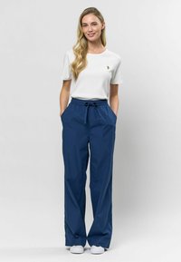 Granatowe, szerokie spodnie z elastycznym paskiem ze sznurkiem w talii i bocznymi kieszeniami, zestawione z obcisłym, białym podkoszulkiem z prążkowanej tkaniny.