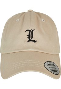Beige pamut baseball sapka állítható pánttal, elöl hímzett fekete "L" logóval és oldalt kerek címkével.