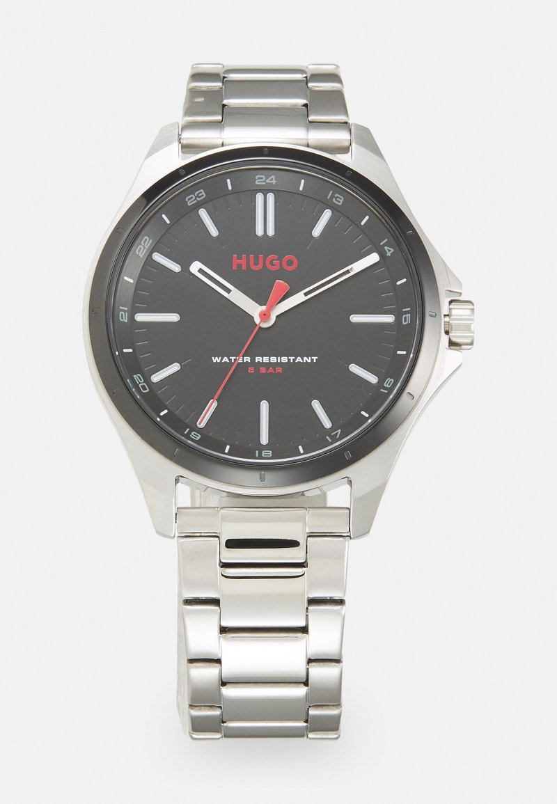 Reloj de acero inoxidable plateado con una esfera negra, acentos rojos y resistencia al agua de hasta 5 bar; cuenta con manecillas de horas, minutos y segundos.