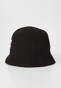 Svart strikket bøttehatt med ribbet tekstur og en liten skygge, med et lite logo-merke på siden.