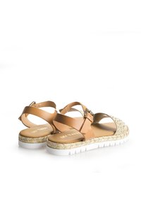 Kellonruskeat nahkasandaalit, joissa on kudottuja tekstuurit yksityiskohtia, säädettävä solki, valkoinen kumipohja ja auki oleva takasuunnittelu.