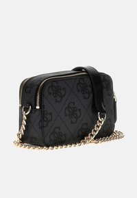 Black patterned crossbody bag with a zip closure, leather strap, and gold chain accents. Rectangular shape and textured material.