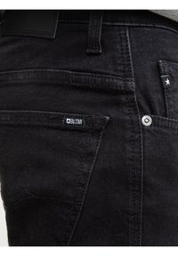 Mustade teksade tagatasku lähivaade, millel on Big Star kaubamärgi silt ja metallist naelutused.