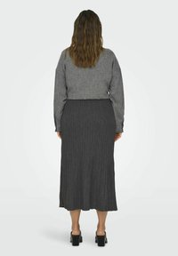 Set di maglione e gonna a coste grigio, con lunghezza cropped e orlo svasato. La texture è morbida e i colori sono neutri e versatili.