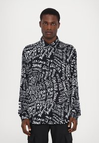 Schwarzes Langarmshirt mit einem weißen Textdruck "Versace Jeans Couture" in verschiedenen Stilen, aus glattem Stoff mit einem geknöpften Kragen.