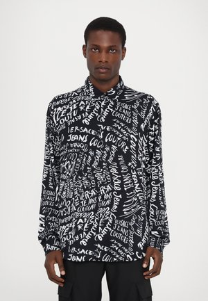 Chemise noire à manches longues avec un imprimé textuel blanc "Versace Jeans Couture" dans différents styles, fabriquée en tissu lisse avec un col boutonné.
