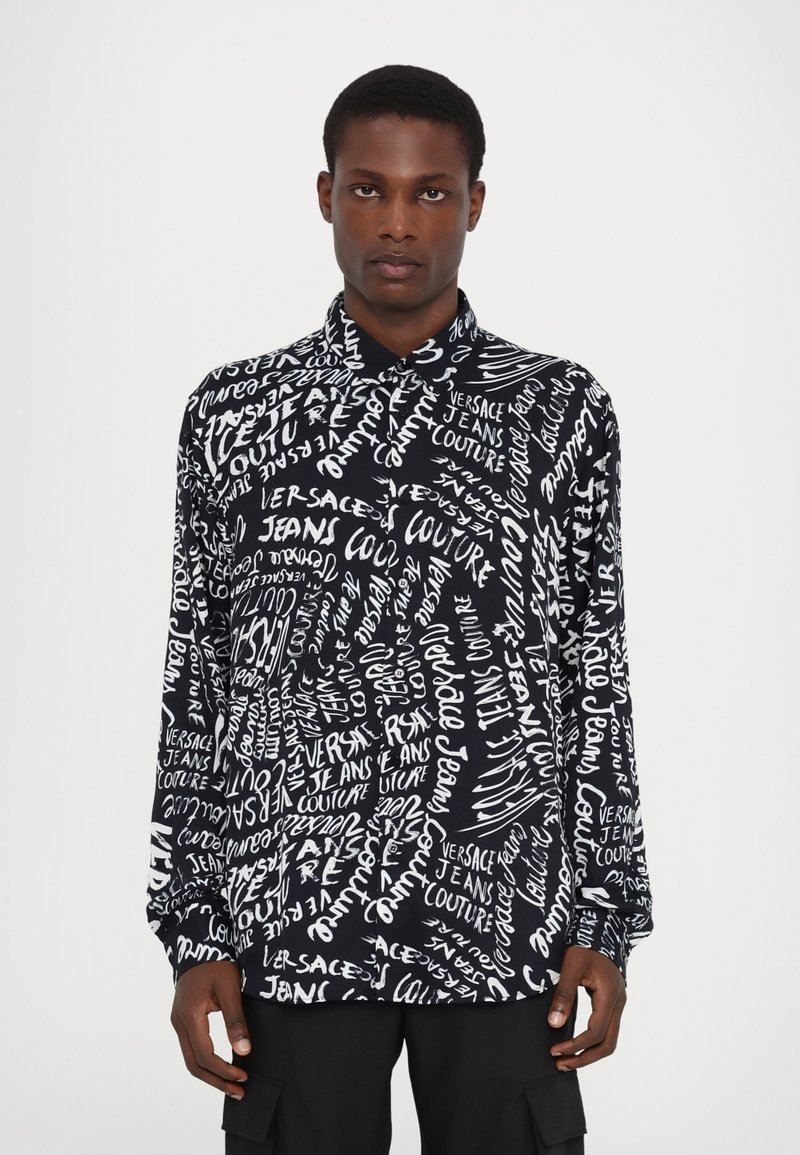 Schwarzes Langarmshirt mit einem weißen Textdruck "Versace Jeans Couture" in verschiedenen Stilen, aus glattem Stoff mit einem geknöpften Kragen.