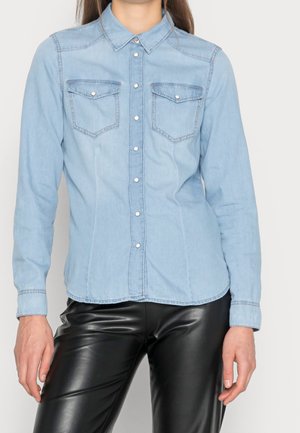 Light blue denim shirt with long sleeves, button-down front, two chest pockets, and contrasting stitching details. Smooth texture.