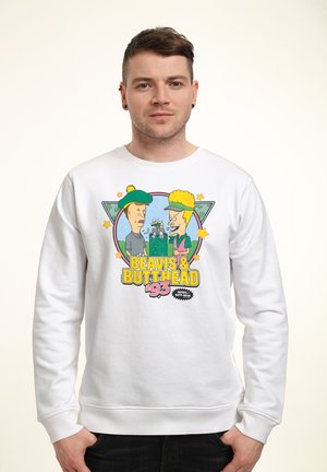 Mężczyzna noszący biały sweter z postaciami z kreskówek Beavis i Butthead oraz napisem "Beavis & Butthead '93" z przodu.