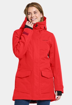 Red waterproof parka with a hood, featuring two large front pockets, a zipper closure, and black sleeve accents. Smooth material, long sleeves.