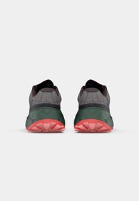 Des chaussures de course avec un dessus en mesh gris foncé, une semelle en caoutchouc verte et une semelle extérieure rouge vif. Elles disposent d'un col rembourré et d'un motif texturé.