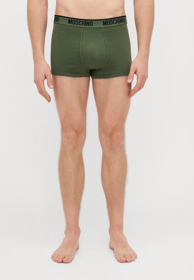 Zelene bokserice s crnim pojasom "Moschino", s uskim krojem i glatkom teksturom. Nema vidljivih uzoraka ili akcenta.