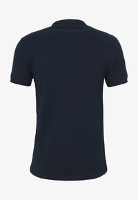 Námorně modré polo tričko s krátkým rukávem zobrazené zezadu, s klasickým límečkem a bez viditelných log nebo vzorů.