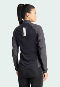 Czarnie i szare sportowe kurtki z długim rękawem, z siateczkowego materiału, z trzema białymi paskami na górnej części pleców oraz dopasowanym krojem.