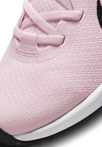 Baskets de sport rose clair avec une tige en mesh texturée et des accents lisses, dotées d'une semelle blanche et d'une semelle extérieure noire, et de lacets plats.