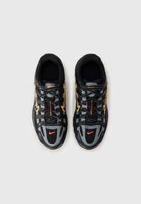 Chaussures de sport noires et grises avec des accents jaunes et rouges. Comprend une tige en synthétique, des panneaux en maille et un motif de semelle distinct.