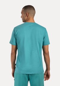 T-shirt turchese a maniche corte realizzato in tessuto morbido, con scollatura rotonda e vestibilità rilassata. Texture liscia con dettagli minimi.