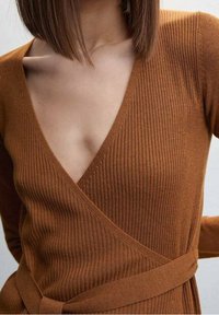 Robe en tricot côtelé marron avec un décolleté en V profond et des manches longues. Dotée d'une ceinture à nouer à la taille et d'un tissu lisse et texturé.