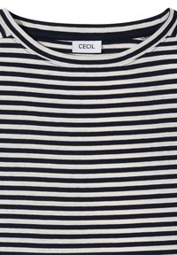 Gros plan sur l'encolure d'un t-shirt à rayures horizontales noires et blanches avec une étiquette de vêtement "CECIL".